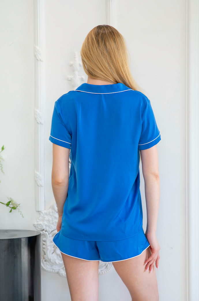 Stylish back view of a satin pajamas set from a leading pajama manufacturer, featuring a blue short-sleeve button-up top with white trim and matching shorts, designed for a comfortable and elegant sleepwear experience