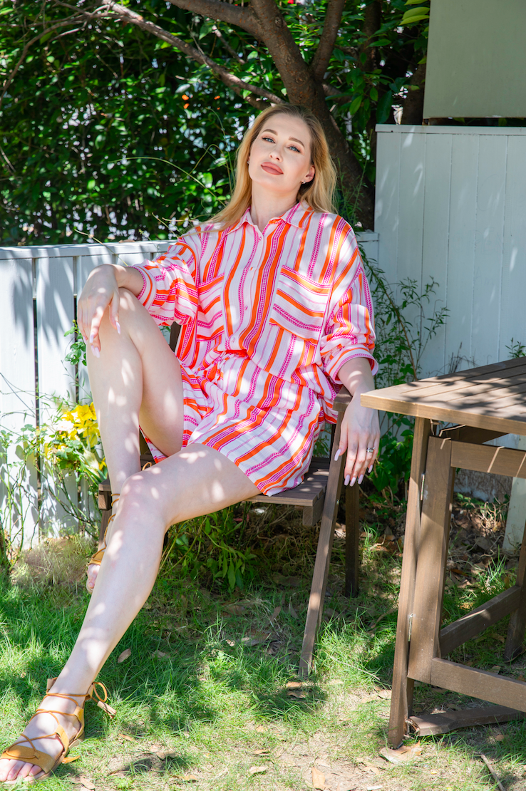 Vibrant pink and white viscose pajama set from a leading sleepwear factory, featuring a relaxed outdoor pose with a buttoned shirt and shorts, crafted by expert pajamas manufacturers.